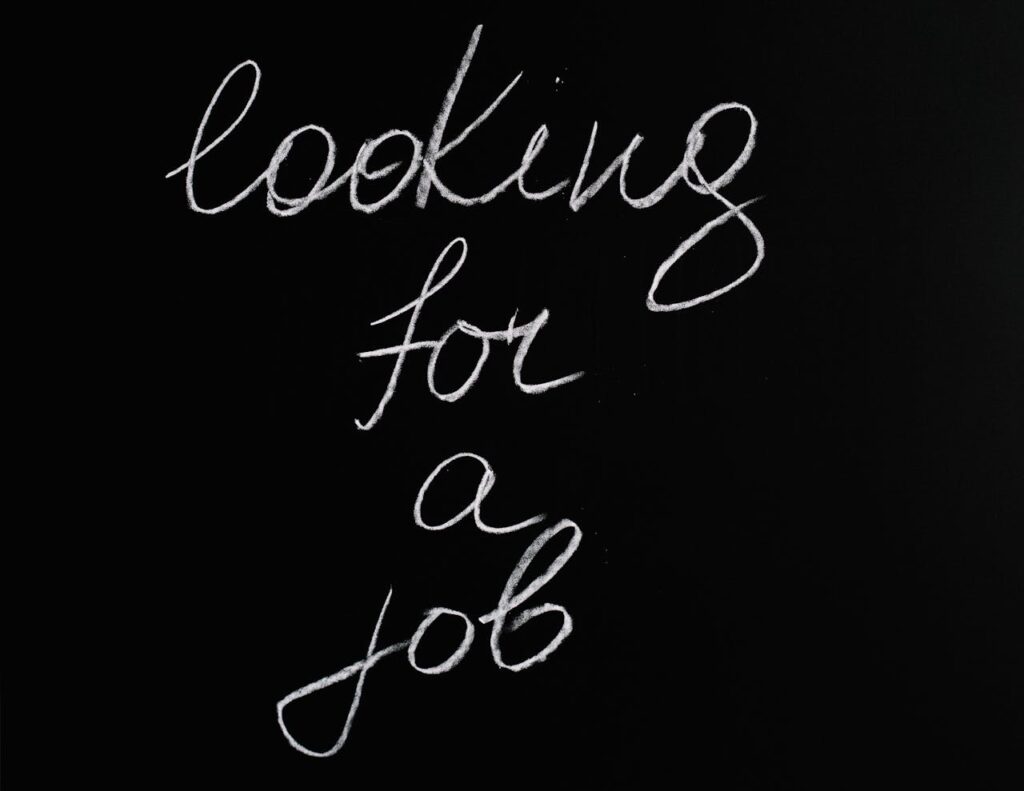 Cursive 'looking for a job' text on a black chalkboard, conveying job search concept.