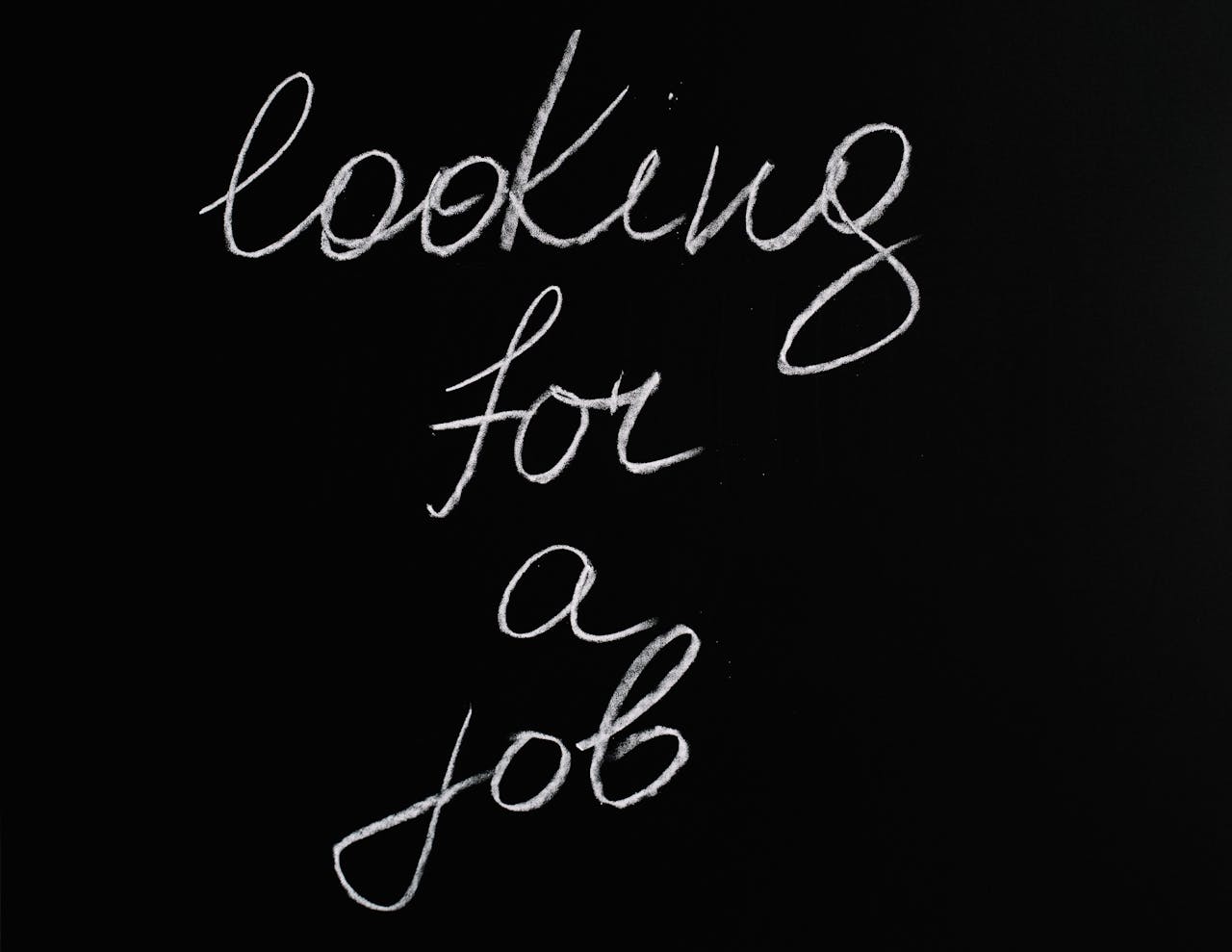 Cursive 'looking for a job' text on a black chalkboard, conveying job search concept.